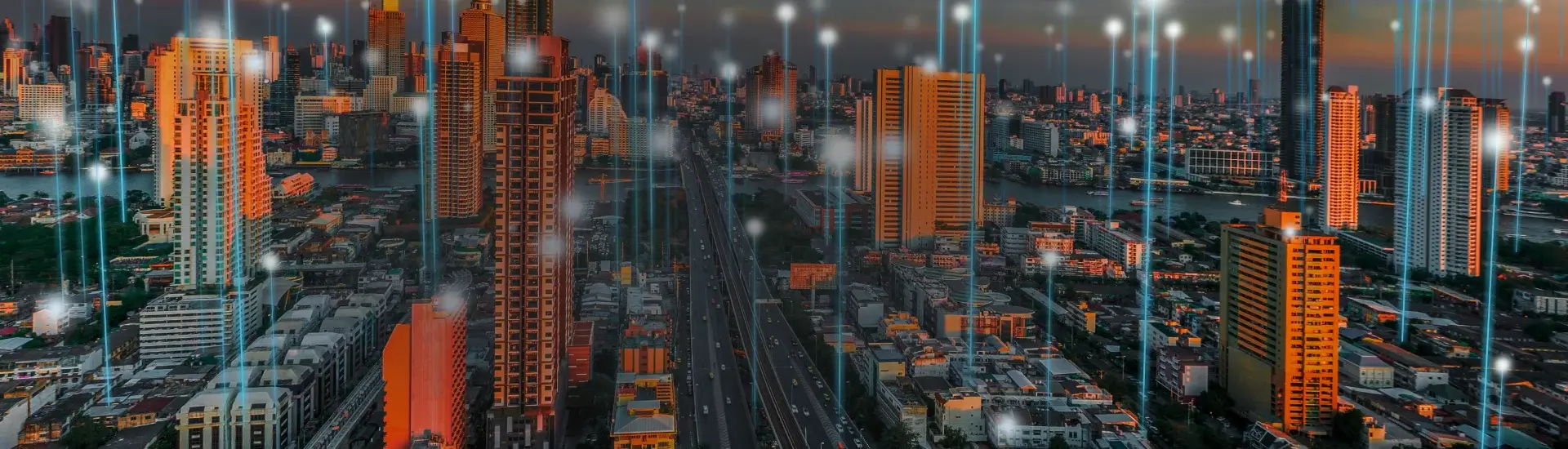 Imagem de cidade com grandes prédios e feixes de luz, que ilustram conexão, indo em direção ao céu