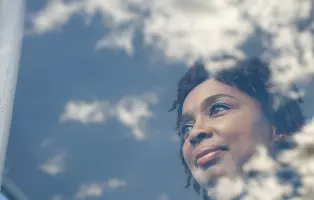 Imagem de mulher observando o céu através de janela para ilustrar OSS.